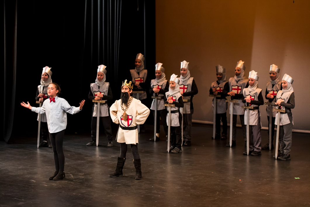 Group of students performing on stage dressed as knights