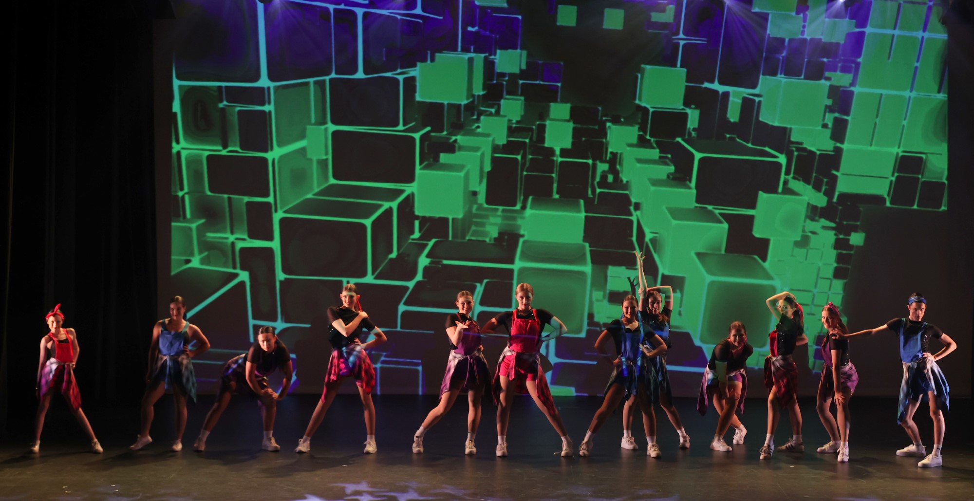 A high school dance performance with a colourful green background
