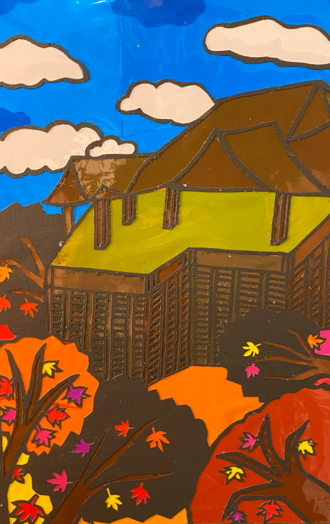  A layered paper-cut artwork, with a blue sky and white fluffy clouds in the background, a traditional single tier japaenese pagoda roof, and autumn coloured trees of dark brown, orange and red in the foreground