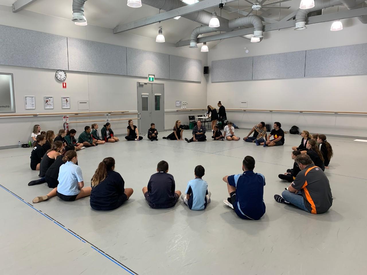 Students sitting in a large circle at the start of the Aboriginal Dance Workshop
