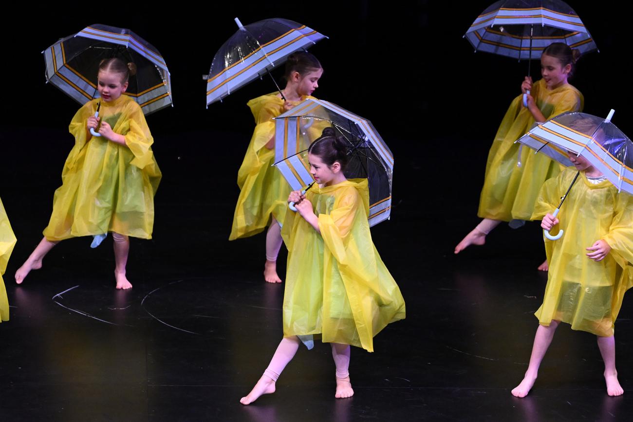 students dancing in yellow raincoats and umbrellas 