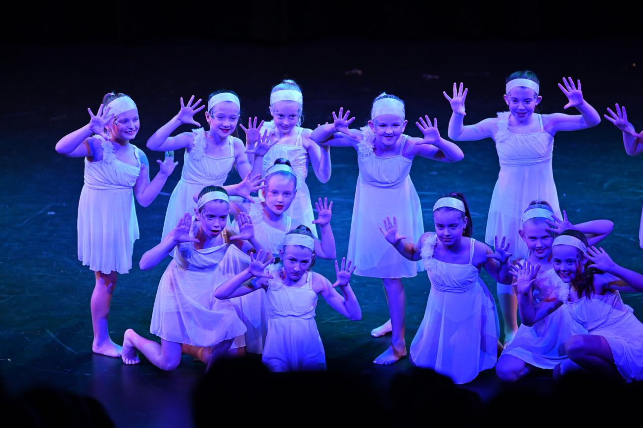 students in pose on stage in white dresses