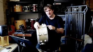 David Lockeridge in his music studio, holding a drum.