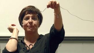 Lisa Van Den Dolder holding up a long wire bent into a number of loops.