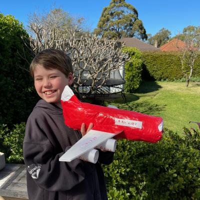 student holding a red plane made from cardboard